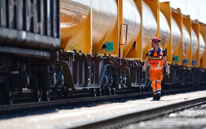 A DB Cargo employee walks alongside a tank car train